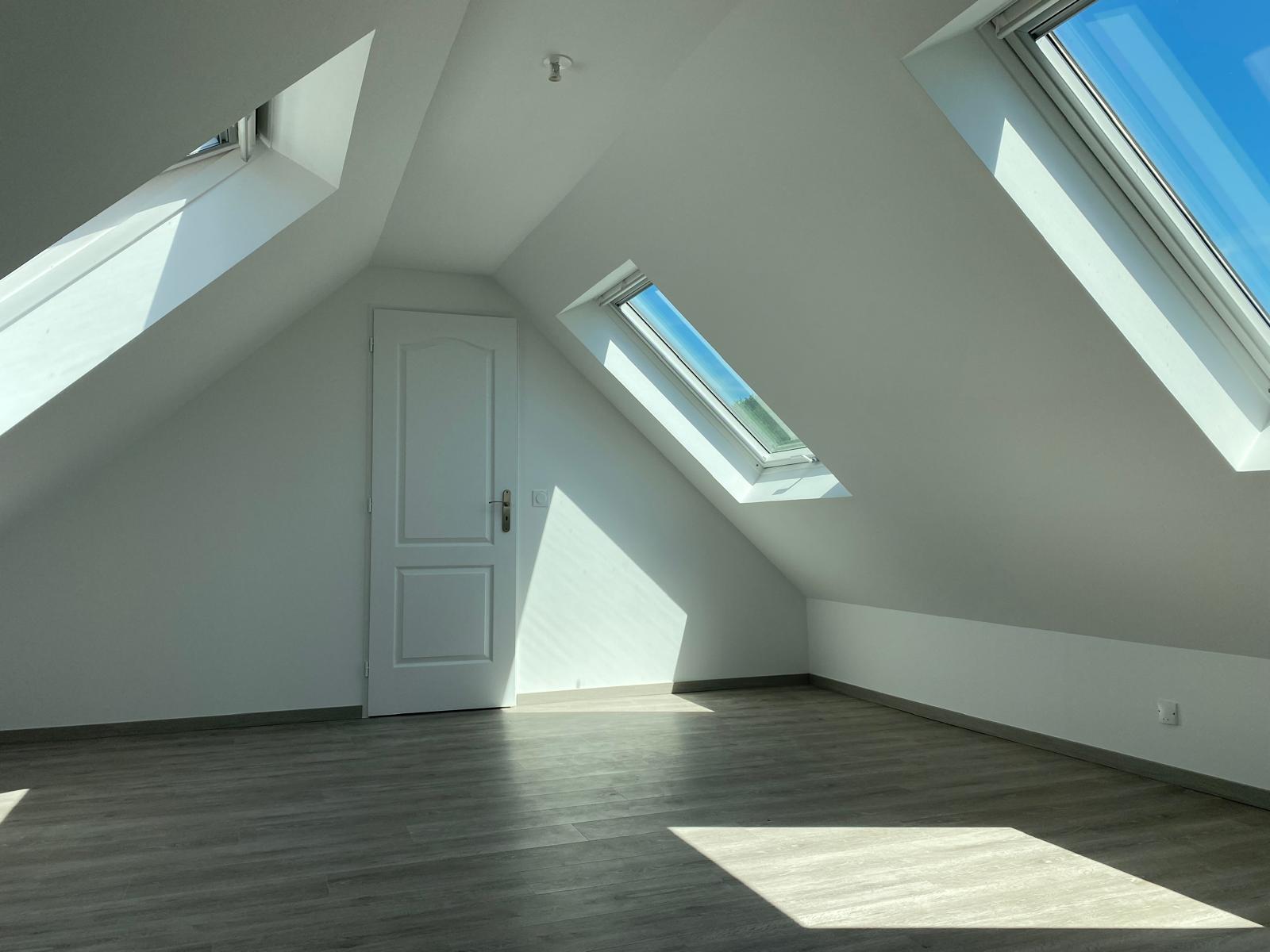 Réalisation Prima Combles : pièce lumineuse sous les toits avec trois fenêtres de toit